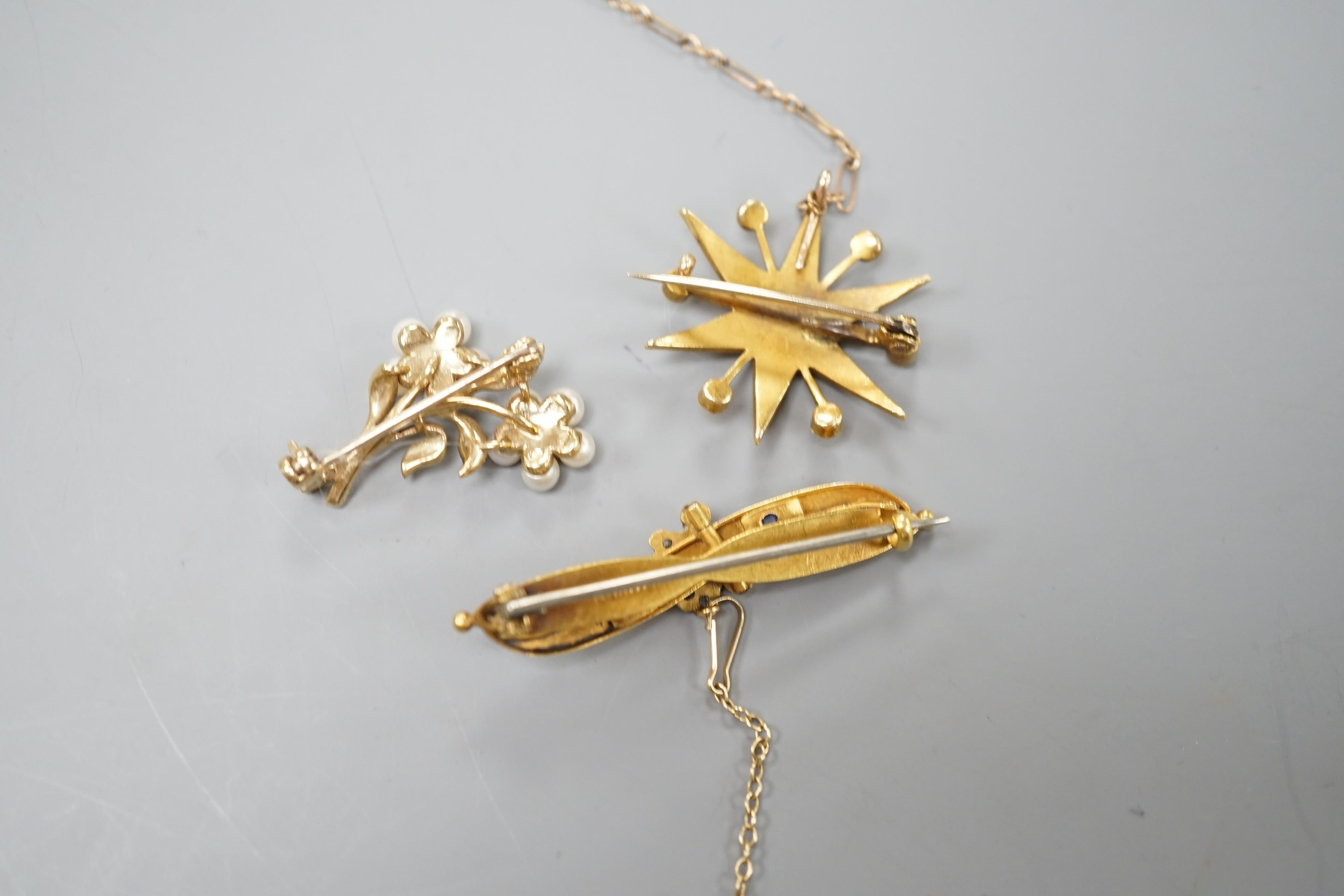 A late Victorian 15ct gold and sapphire set bar brooch, 44mm, gross weight 3.5 grams, an Edwardian yellow metal and split pearl set starburst brooch, gross weight 4.6 grams and a modern 9ct gold and gem set twin flower b